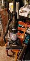 Eureka AirSpeed upright vacuum displayed on a chair