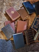 Top-down view of 11 leather bound books showing various colored covers and gold embossed spines