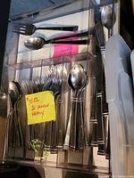View of heavy silverware flatware set in clear tray showing forks, knives, and spoons neatly arranged. A yellow sticky note indicates 31 pieces and price $15.