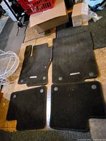 Set of four black velour car floor mats laid out on floor showing front and rear mats.
