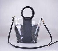 Black and clear bucket bag with double round handles, detachable interior pouch, and long strap shown on a white background.