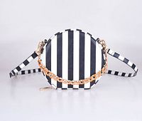 Front view of the round crossbody bag with black and white vertical stripes and red chain link strap, showing design and materials.