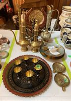 Photo of brass and enamel serving items including pitchers, plates, tray with six aperitif glasses, and decorative bowl