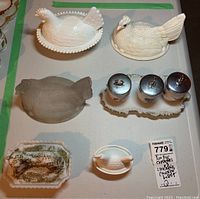 Top-down view showing 2 chicken bowls (one white glazed, one unglazed), vintage lidded lamb butter dish with paint loss, 3 egg coddlers with metal lids on a ceramic tray.
