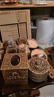Overview photo showing the set of metal jewelry tray and dresser boxes, tissue box cover, jars, and small tray placed on a wooden surface.
