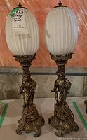 Front view of the two vintage table lamps showing frosted ribbed glass shades and metal bases with cherub figures.