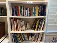 Three shelves filled with a variety of books with different colors and sizes.