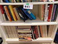 Photo showing two shelves filled with various books. Titles visible include 'Every Day Cook Book', 'The Second Sex', 'The Prophets', 'The Social Animal', and works by Umberto Eco.