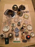Photo showing top-down view of assorted items including silver plate pieces, crystal bowls, Wedgwood and Aynsley porcelain, and other decorative items.