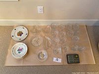 Overview of all items laid out on craft paper including dessert dishes, brandy glasses, candy dishes, spreaders, bowls, and plate.