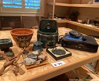 Wide view of the decor items and electronics placed on a wooden table, showing the variety of items in the lot