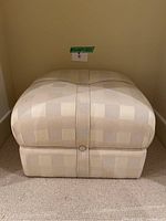 Front view showing beige square ottoman with checkered pattern and central button.