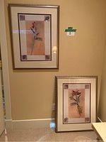 Pair of two framed floral art prints hanging and resting against a wall, showing size and style.
