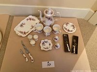 Overall view of tea set and accessories including teapot, cups, tray, dishes, egg cups, salt & pepper, knives and boxed items