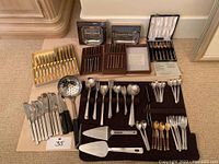 Overall arrangement of loose and boxed cutlery and serving pieces on floor