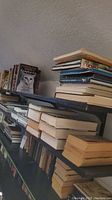 Three shelves filled with stacked softcover and hardcover books, with visible titles such as "The Complete Cat" and some older books.