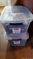 Two stacked clear Rubbermaid Cleverstore plastic storage totes with lids, both filled with books.
