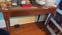 Wooden side table top with various items placed on it, showing the rectangular shape and overall table design.