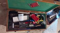 Top view of wood tool box open showing green lining and assorted tools inside.
