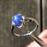 Ring held in tweezers showing star sapphire asterism and prong setting
