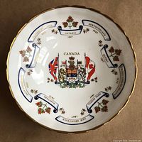 Top view showing detailed Canadian coat of arms, flags, province names and founding years around the bowl interior with maple leaf accents and gold trim.