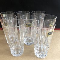 Front view of eight crystal highball glasses arranged in two rows with visible original stickers on some glasses.
