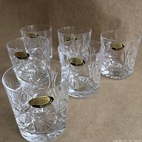 Set of six crystal lowball glasses arranged together showing gold and black Prestige stickers on each glass.
