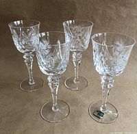 Four vintage stemmed lead crystal wine glasses with detailed hand-cut Pinwheel Star design, photographed upright on a neutral surface.