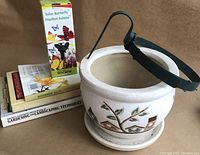 Photo of ceramic planter pot with decorative birdhouses and leaves, black adjustable hanger, solar butterfly box, gardening books, and journal
