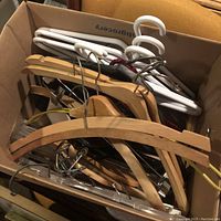 Box filled with assorted hangers showing mix of wood, plastic, and metal parts in close view.