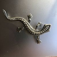 Top view of the pewter lizard brooch showing clear raised texture and detailed limbs.