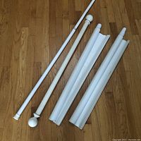 Full view of all four items laid on a wood floor showing the tension shower rod, curtain rod, and two roller shades.