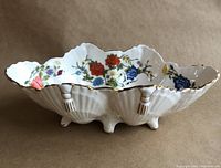 Side view of the oval scalloped Aynsley dish showing the exterior tasselled shell design and gilt-edged feet.