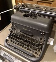 Front view of black Remington Rand Model 17 KMC manual typewriter, showing keyboard with some worn and missing key tops.