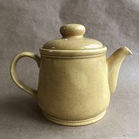 Front view of mustardy ochre Sadler teapot with lid, showing rounded shape, handle and spout.
