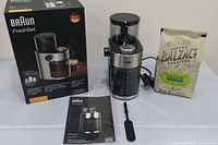 Photo shows Braun FreshSet coffee grinder with its original box, instruction manual, cleaning brush, and a 12 oz bag of Balzac's Roasters Farmer's Blend coffee beans.