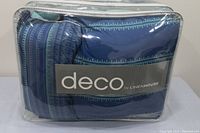 Front view of packaged comforter set with 'deco by LINENHOUSE' label visible under plastic packaging.
