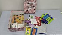 Overview of all craft supplies including box, stamps, ink pads, stickers, wax beads, glitter, colored pencils, and card stock.