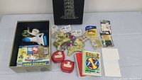 Box with tape dispensers, Play & Practice Pack flashcards, assorted beads, string containers, small notebook, and other small craft supplies.