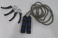 Photo of fitness set showing two hand grip strengtheners and a jump rope with cushioned handles.