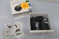 Top view of open Google Chromecast Ultra box showing black streaming device, power adapter with USB cable, and instruction card with setup steps alongside the packaging box.