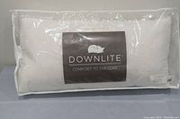 Front view of white feather filled pillow by Downlite in clear packaging showing brand and size label.