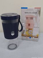 Navy blue portable wireless juicer blender alongside its product box showing color options and branding.