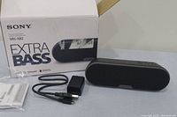 Sony SRS-XB2 Extra Bass speaker with original box, charger, and manuals displayed on table