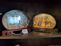 Both Chinese dioramas side by side on shelf showing full view and wooden frames with glass fronts