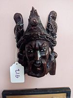 Front view of the carved wood wall mask showing face and crown