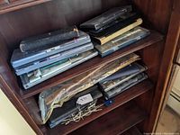 Various stacked cases containing drafting instruments and tools on bookshelf.
