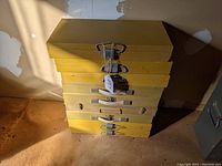 Stack of six yellow metal slide boxes with lock handles