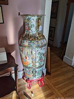 Full view of vase on stand showing overall height and placement next to furniture