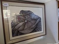 Framed limited edition print in black-brown wood frame, matted, showing full artwork of two intertwined figures